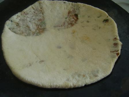 Heat a pan on medium flame. Add the rolled flat-bread to the heated pan.